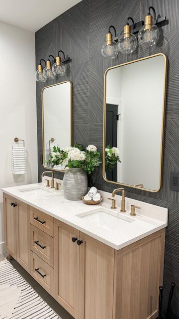 a bathroom with two sinks, mirrors and lights on the wall above them is decorated in black and white