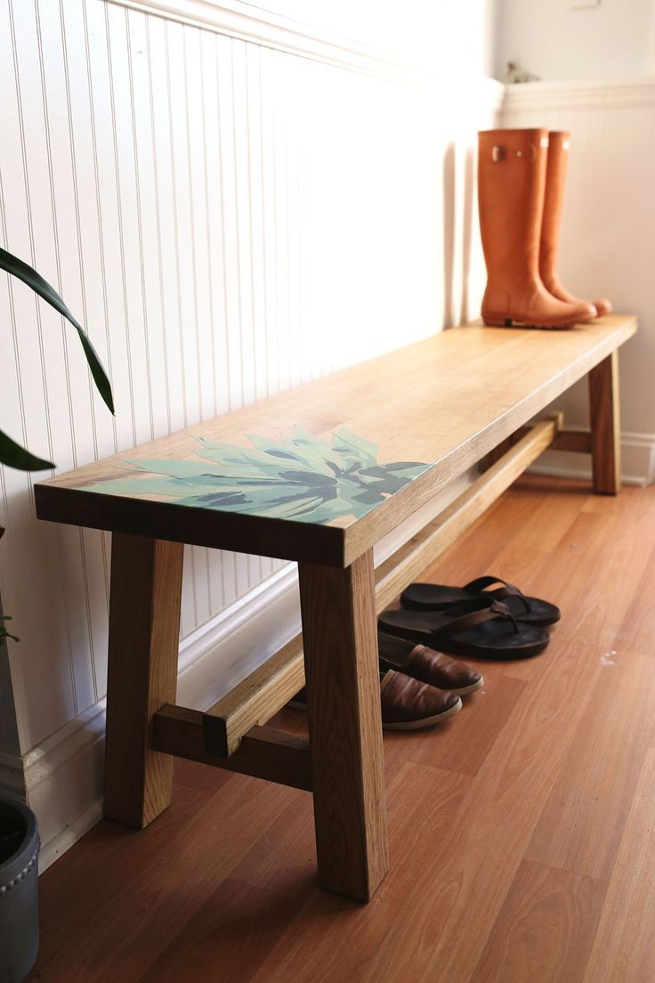 a wooden bench sitting next to a pair of shoes on top of a hard wood floor