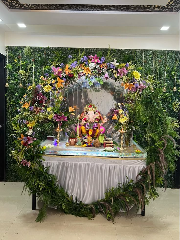 there is a table with flowers on it and a buddha statue in the center surrounded by greenery