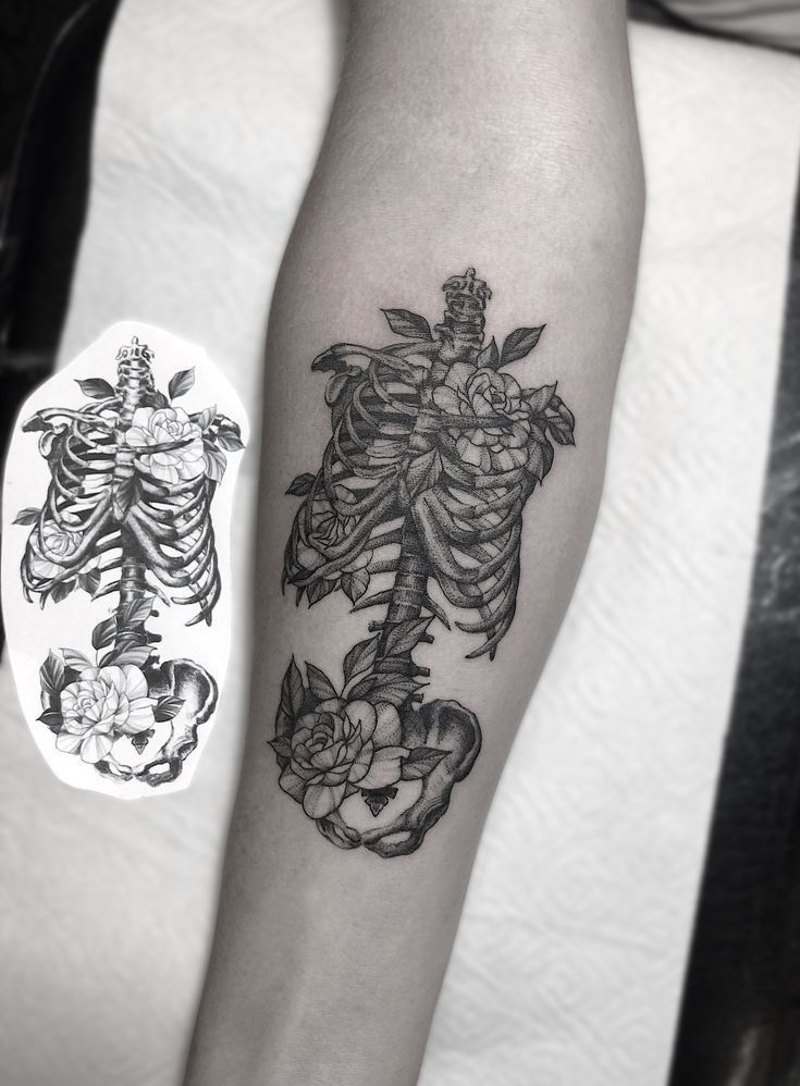 a black and white photo of a skeleton tattoo on the left arm with roses around it