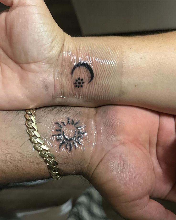 two people with matching tattoos on their wrists, one has a sun and the other has a moon