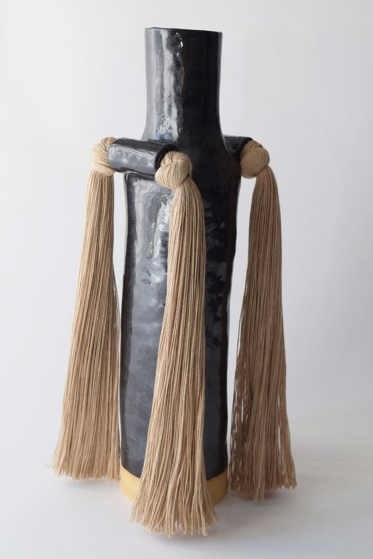 a tall black vase with tassels on it