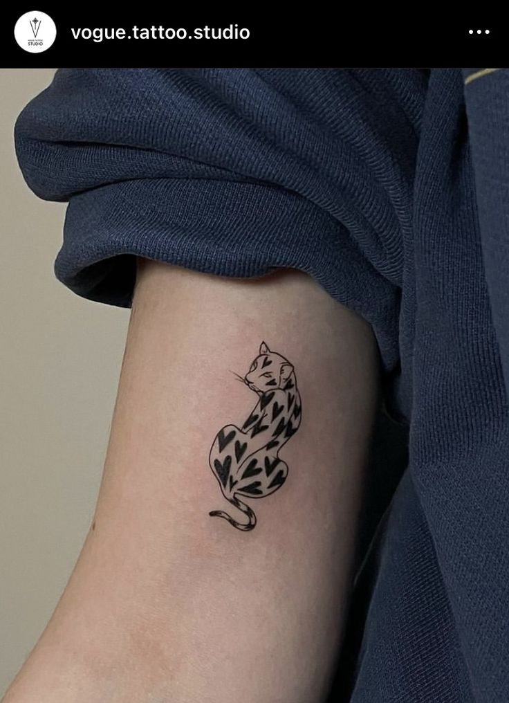 a black and white cat tattoo on the arm