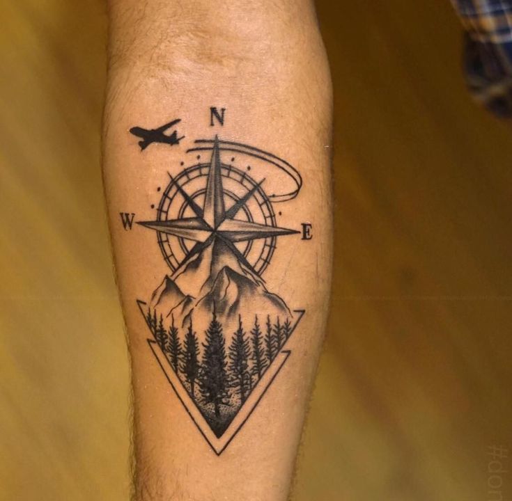 a man's leg with a compass and pine trees tattoo on the side of his calf