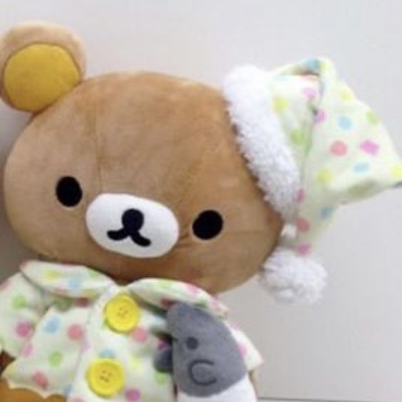 a brown teddy bear wearing a white and yellow polka dot shirt with a hat on