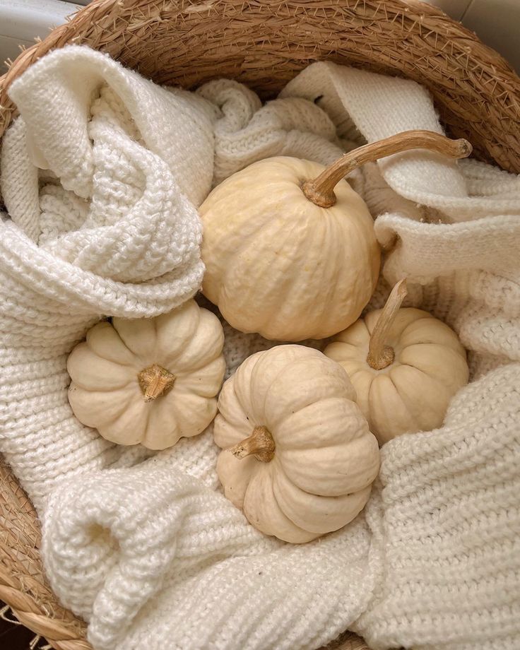 a basket filled with white pumpkins on top of a table