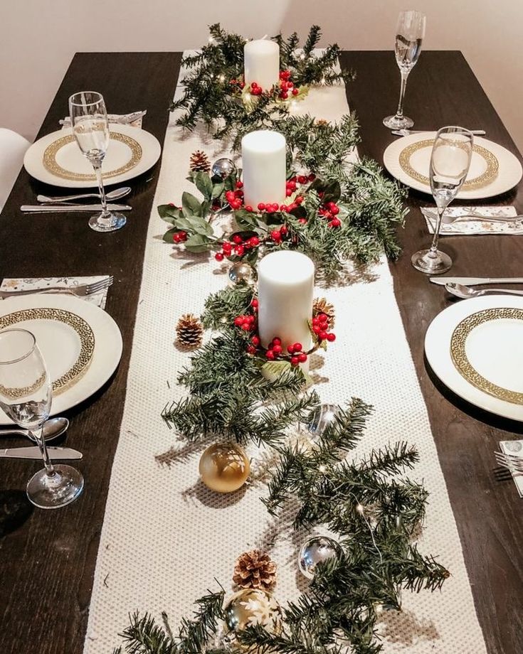 the table is set for christmas dinner with pine cones and greenery