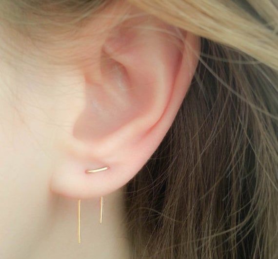 a close up of a person wearing a pair of ear piercings with gold posts