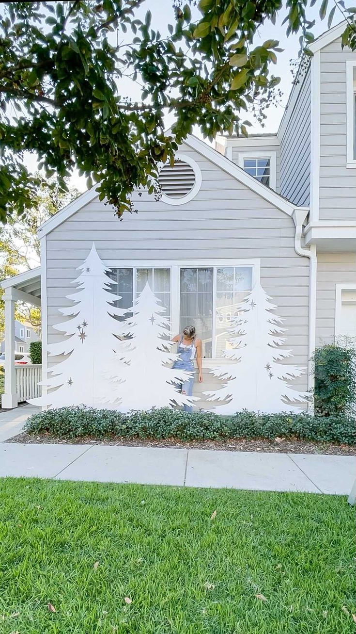 a person standing in front of a house with trees painted on the side of it