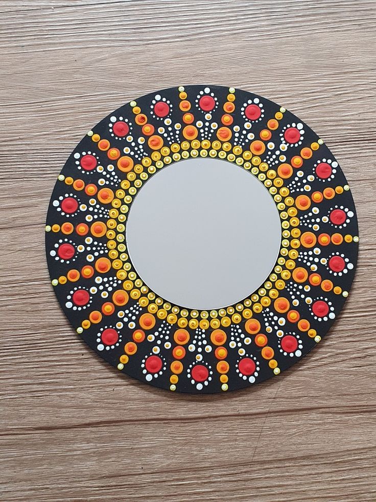 a round mirror on top of a wooden table with circles painted on the surface around it