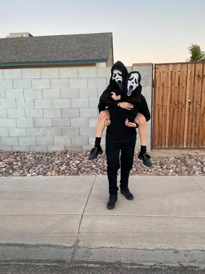 a man in a black hoodie and mask holding another person with their arms wrapped around each other