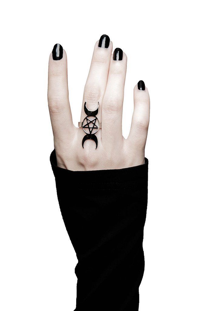 a woman's hand with black and white nails holding up a pentagramil tattoo