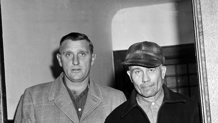 two men standing next to each other wearing hats