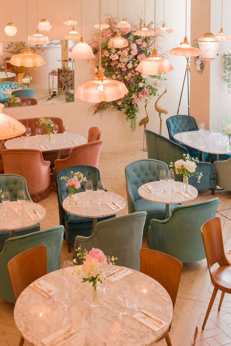 the interior of a restaurant with tables, chairs and chandeliers hanging from the ceiling