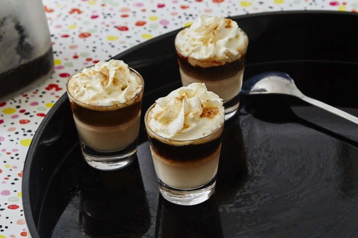 three glasses filled with ice cream sitting on top of a black plate