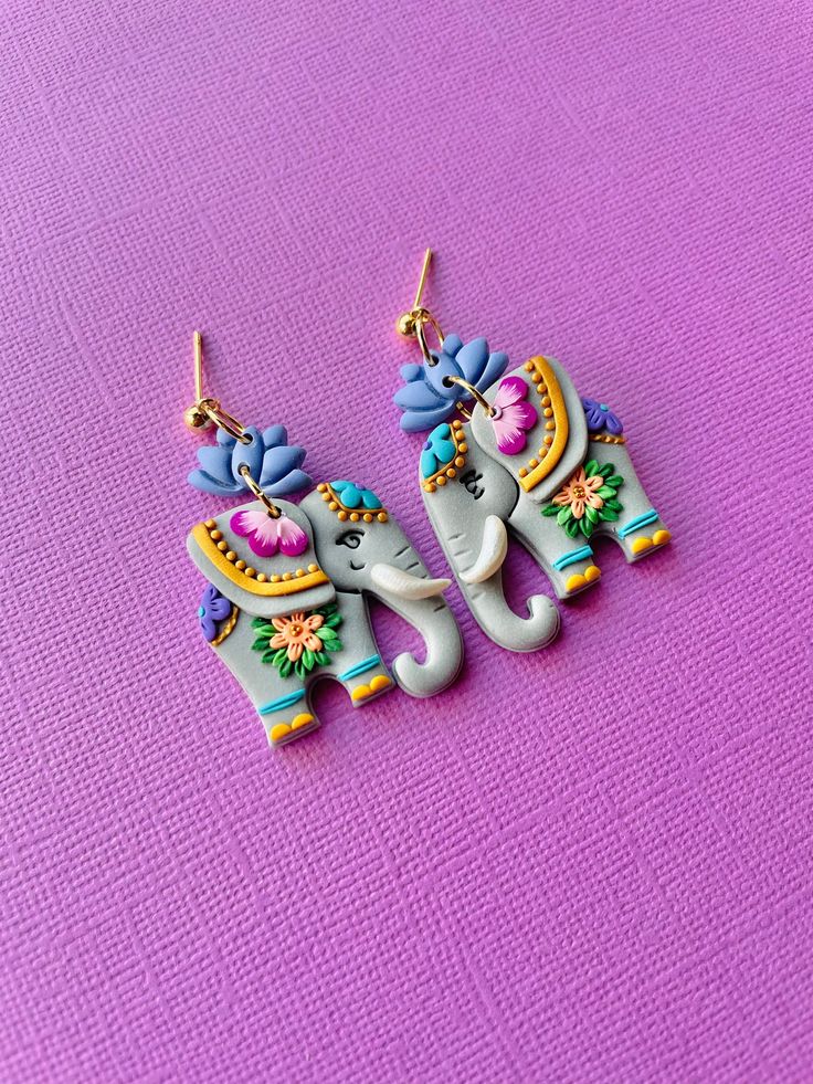 an elephant shaped earrings on a purple surface