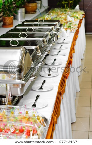 buffet table with many plates and silver trays on it, ready to be served