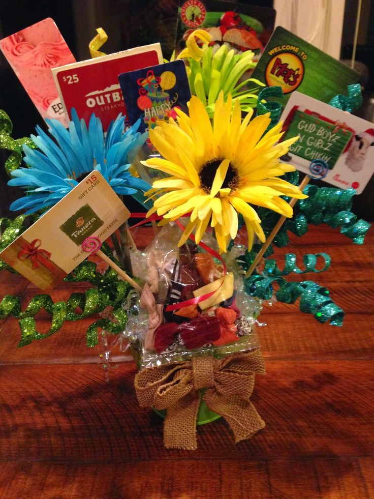 a vase filled with yellow and blue flowers on top of a wooden table next to books