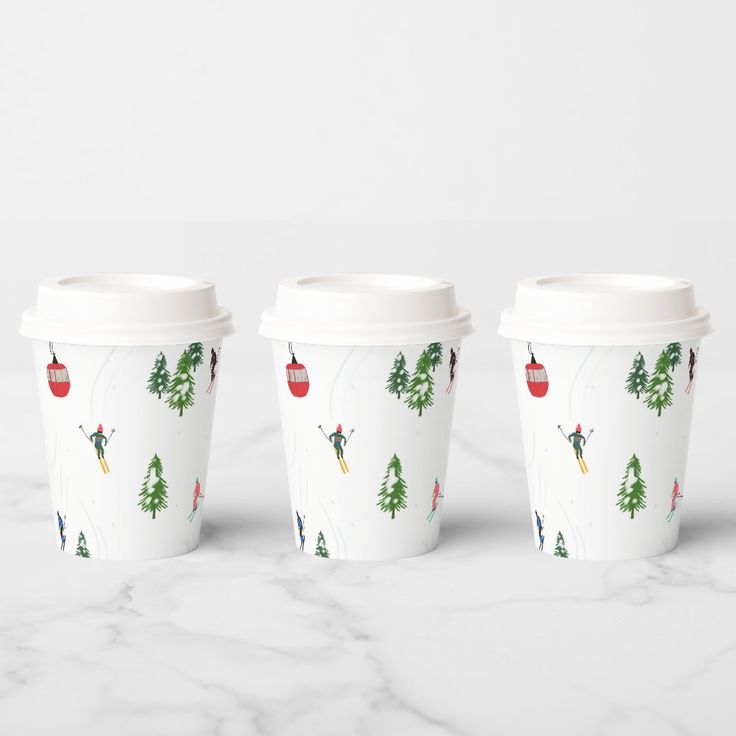 three coffee cups sitting on top of a marble counter next to each other with christmas decorations