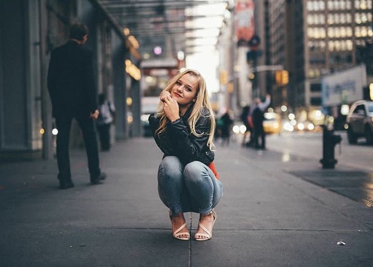 a woman squatting down on the sidewalk