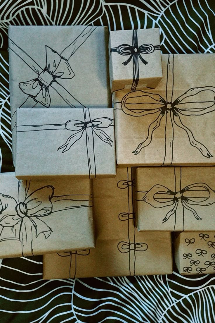 six wrapped gift boxes with bows on them sitting on top of a table covered in black and white paper