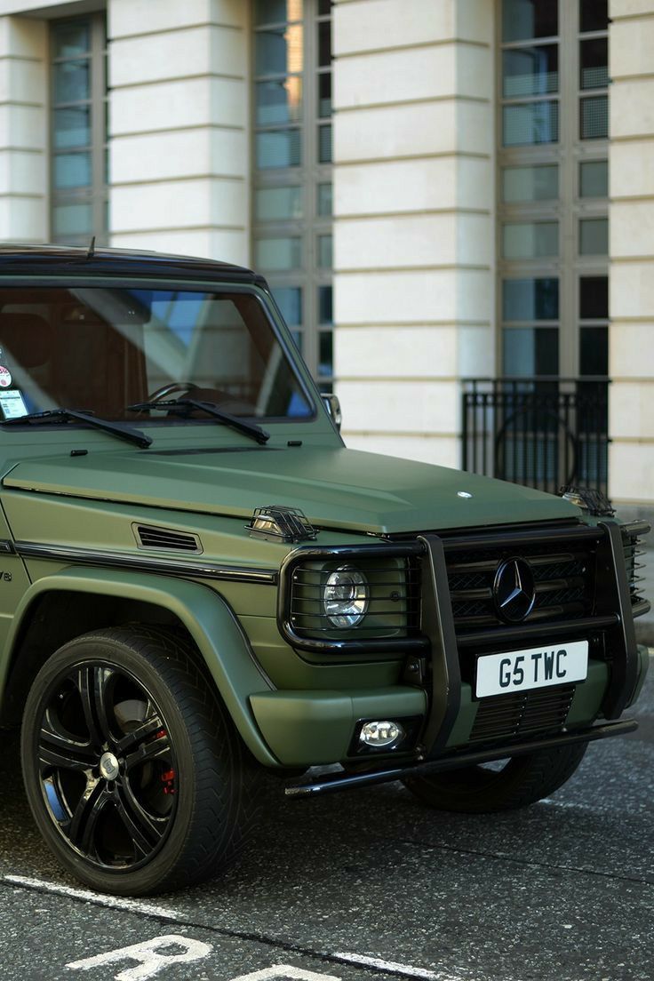 a green suv parked in front of a building