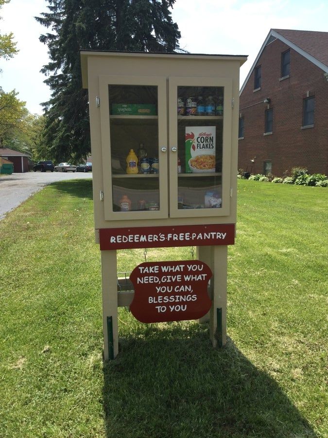 a sign that is on the grass in front of a building with an ice cream dispenser