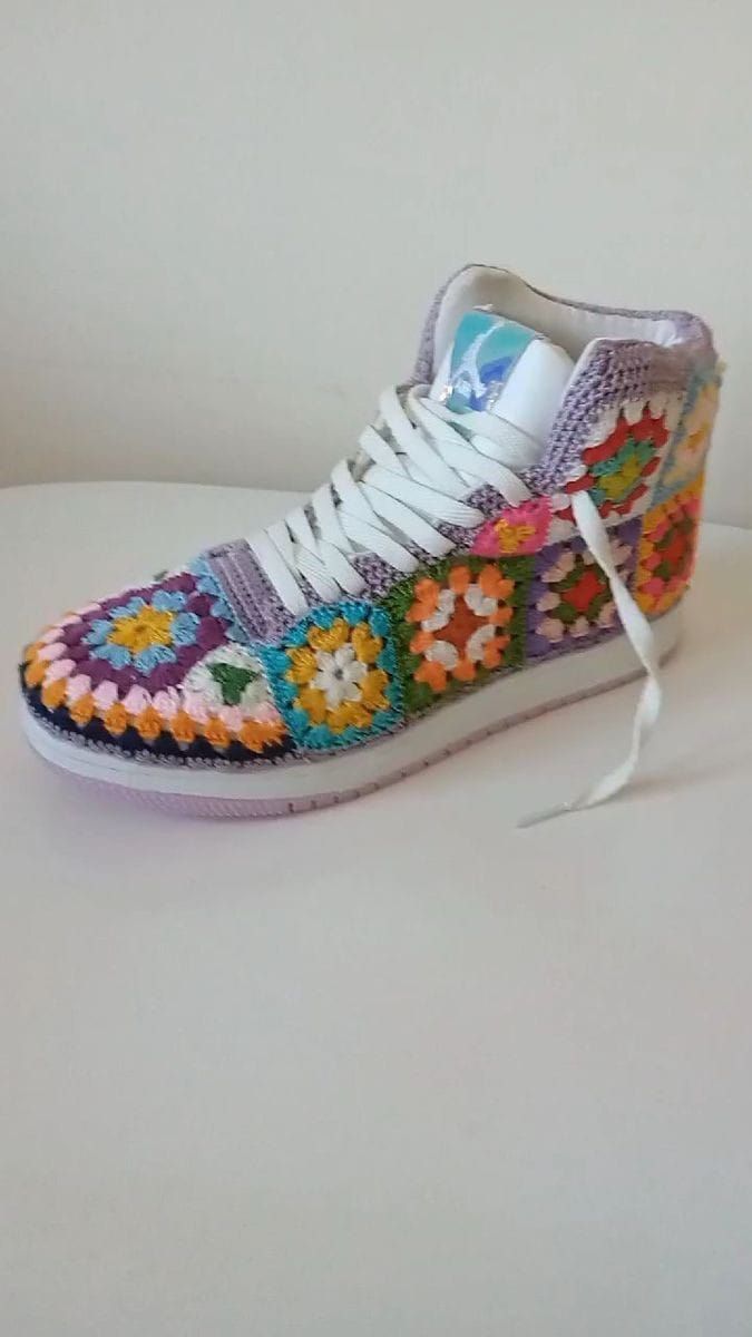 a pair of shoes with colorful crochet on the side and white laces