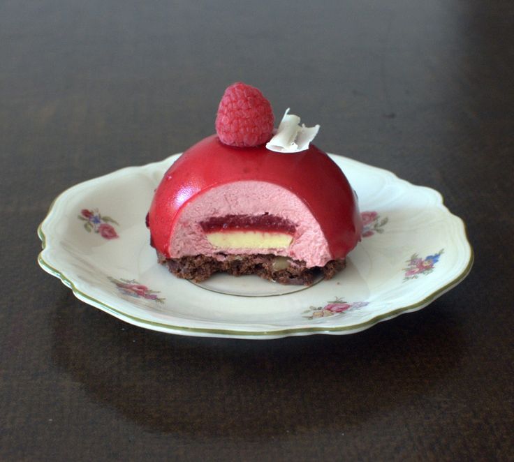 a piece of cake on a plate with raspberries and cream in the middle