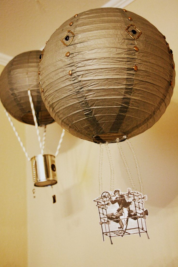 two paper lanterns hanging from the ceiling with chains attached to them, and one is being suspended