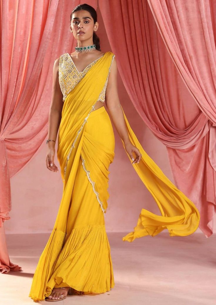 Embellished choli paired with a pre-stitched tiered sari with embellishment on pallu. Traditional Draped Sharara With Mirror Work, Draped Sharara With Mirror Work For Diwali, Diwali Sharara With Mirror Work And Draped Style, Festive Draped Sharara With Mirror Work, Anarkali Draped Embellished Lehenga, Anarkali Style Draped Embellished Lehenga, Anarkali Style Embellished Draped Lehenga, Bollywood Style Draped Sharara With Mirror Work, Festival Draped Choli With Mirror Work