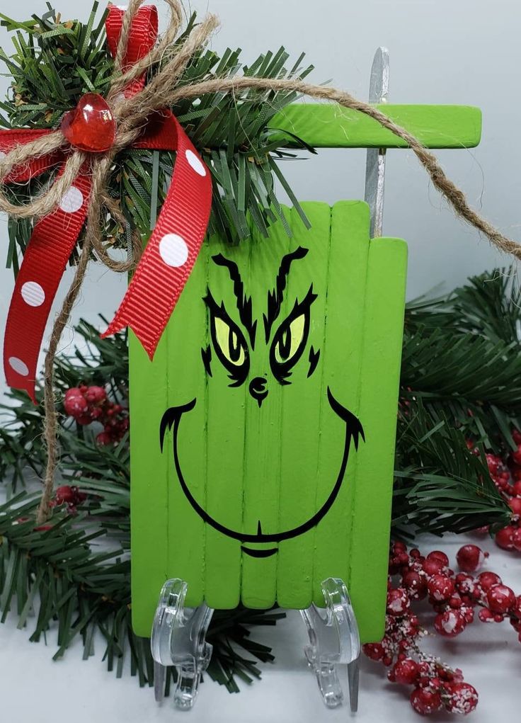 a green christmas ornament with a grin face painted on it's side