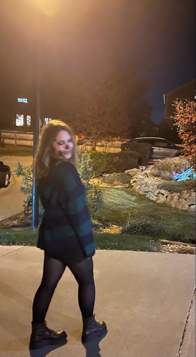 a woman is walking down the sidewalk at night