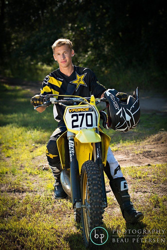 a young man sitting on top of a dirt bike in the middle of a field