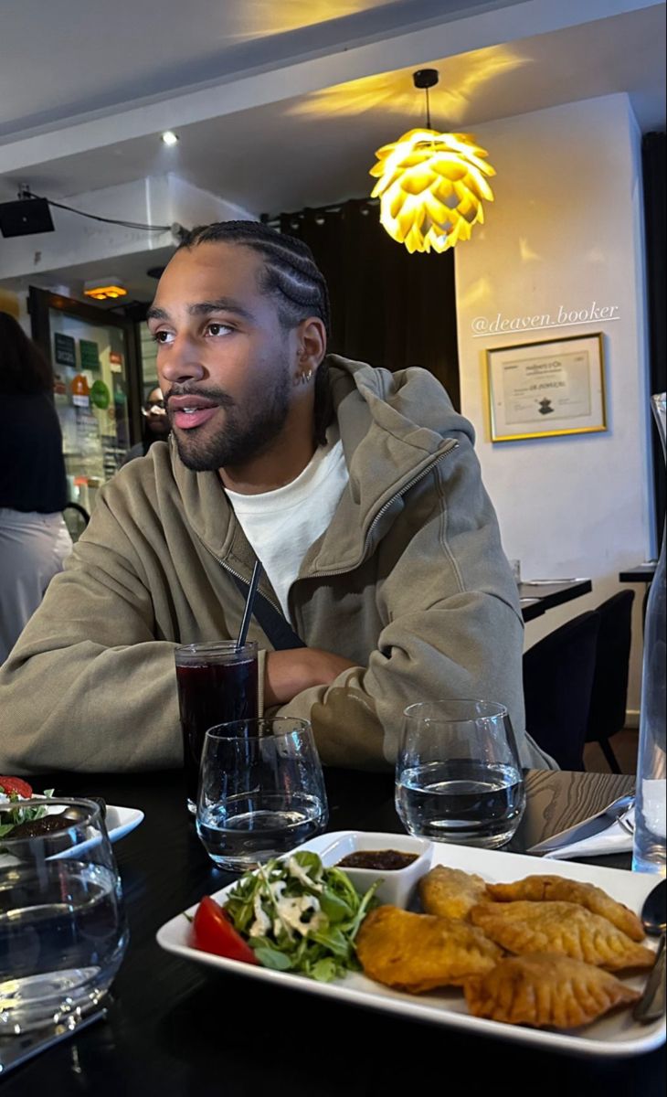 a man sitting at a table with food in front of him and wine glasses on the table