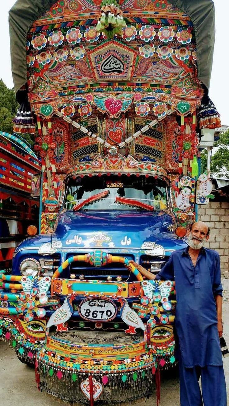 a man standing in front of a truck decorated with colorful decorations on it's side