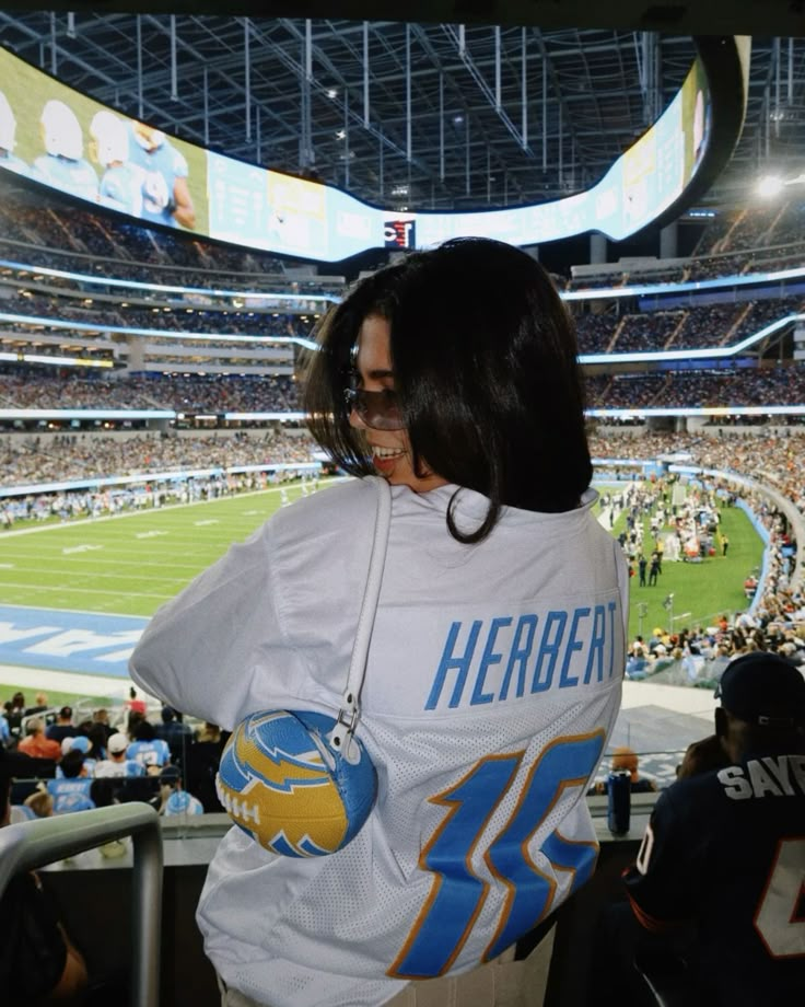 a woman is standing in the stands at a football game wearing a jersey that says herben