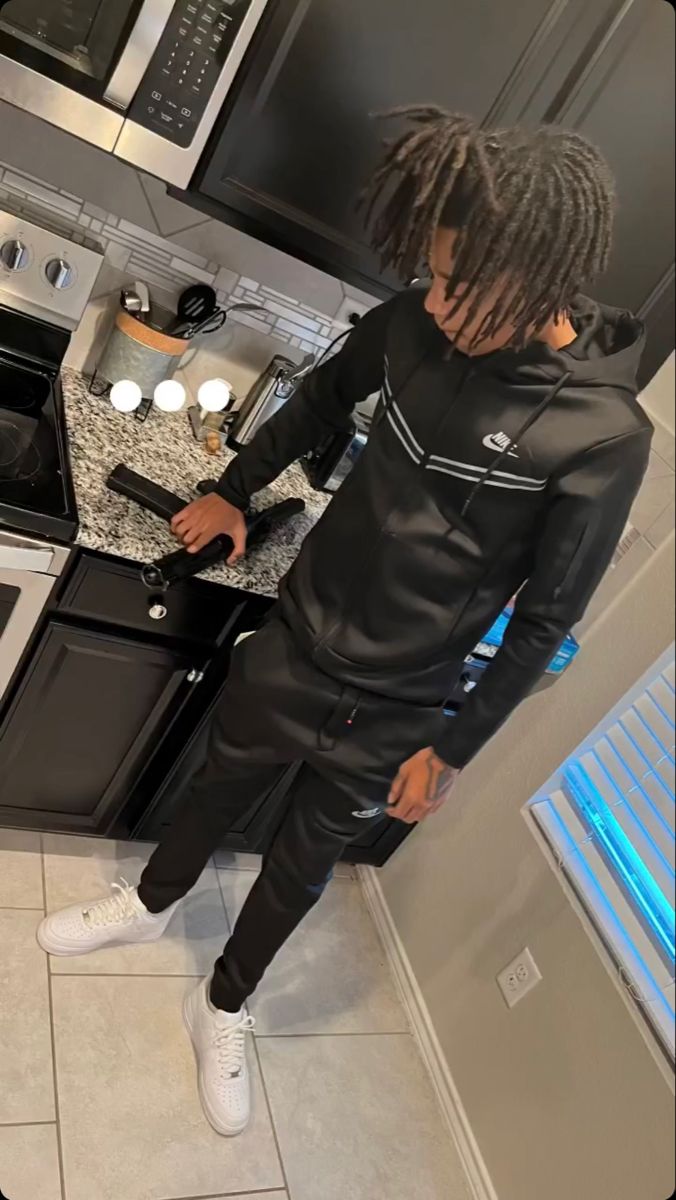 a man with dreadlocks standing in a kitchen next to an oven and microwave