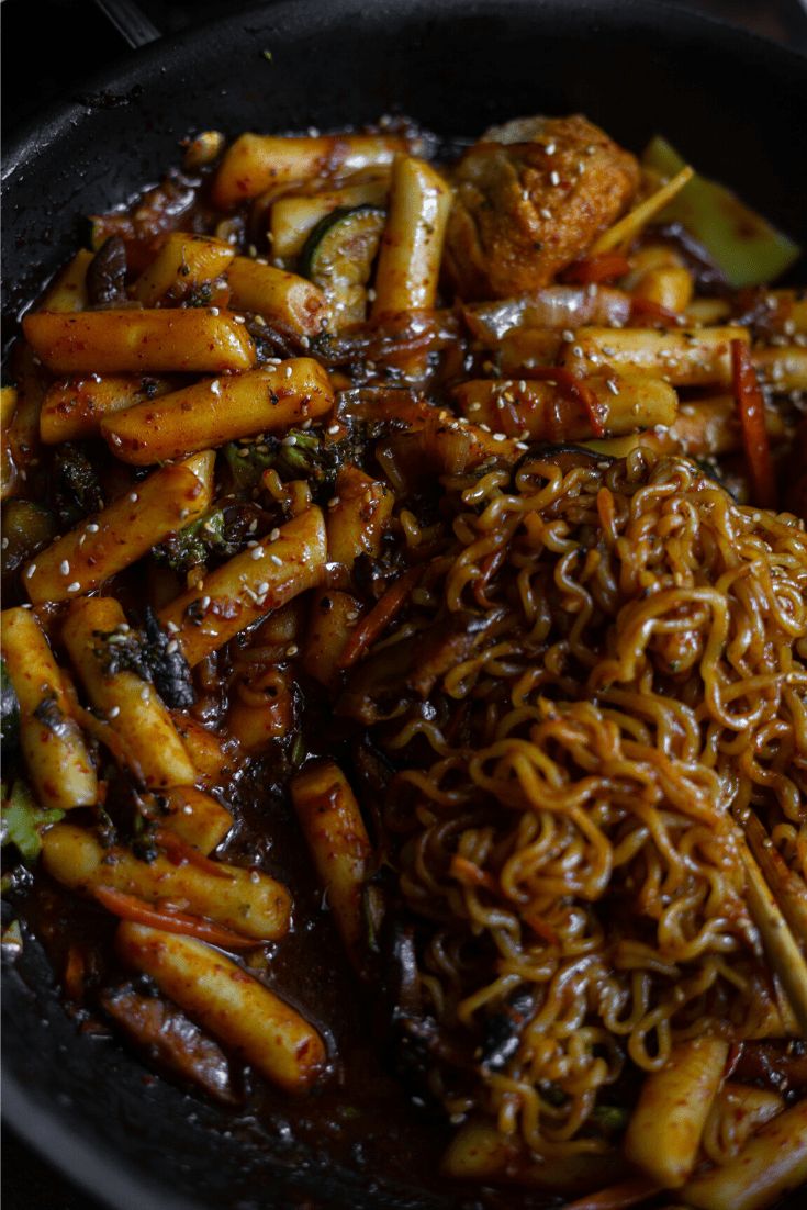 some noodles and vegetables are in a black bowl