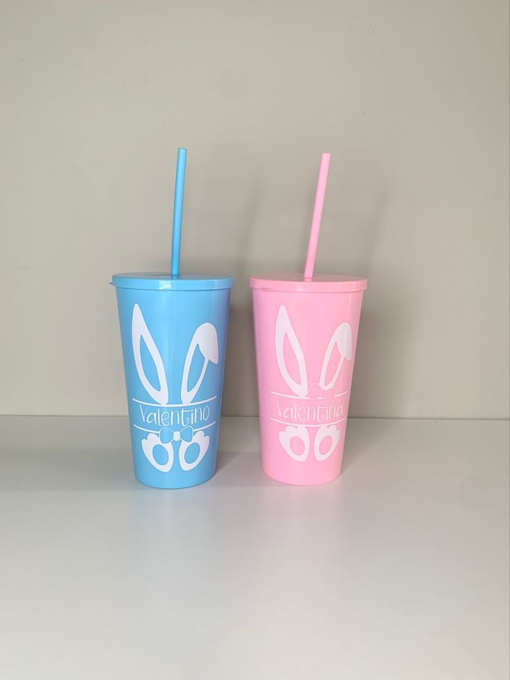 two plastic cups with straws are sitting on a table