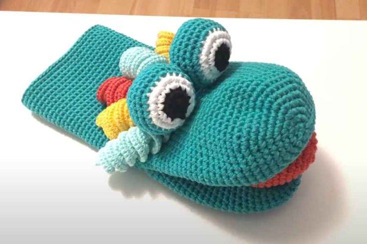 a crocheted blue object with an eyeball on it's side sitting on top of a table