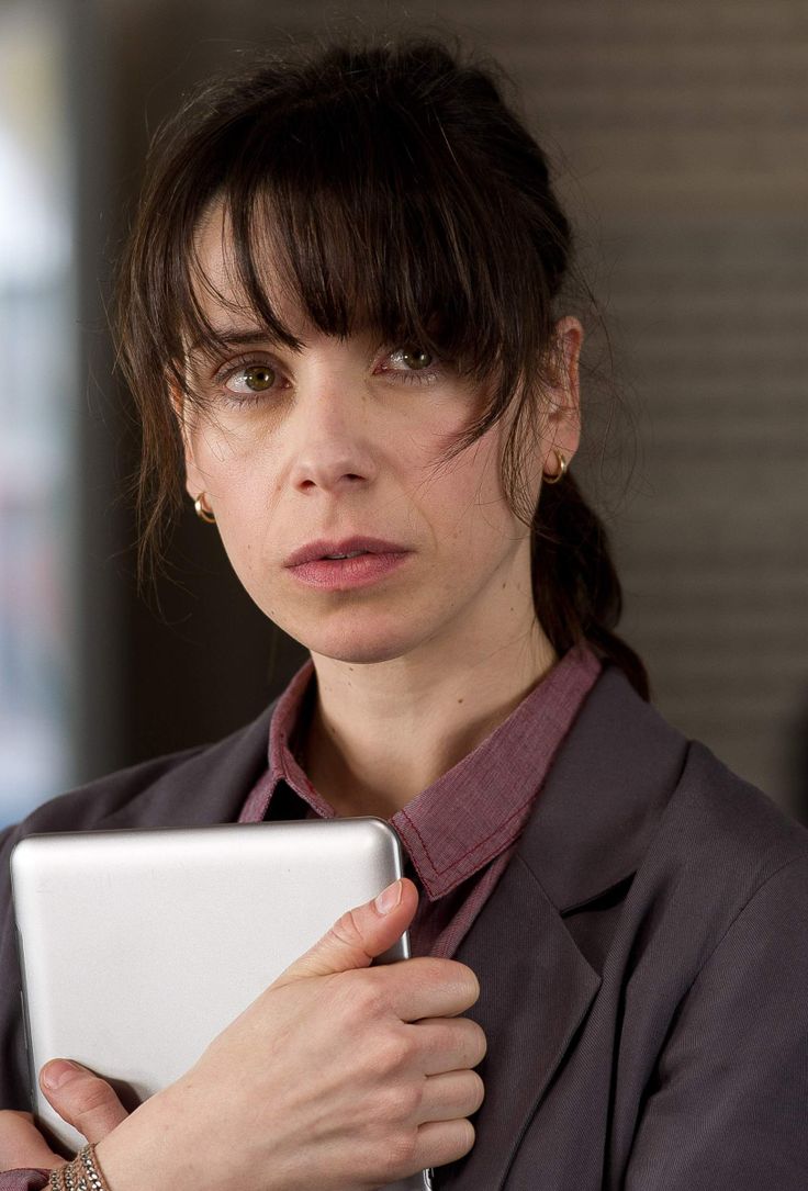 a woman is holding a tablet in her hands and looking at the camera while standing next to other people