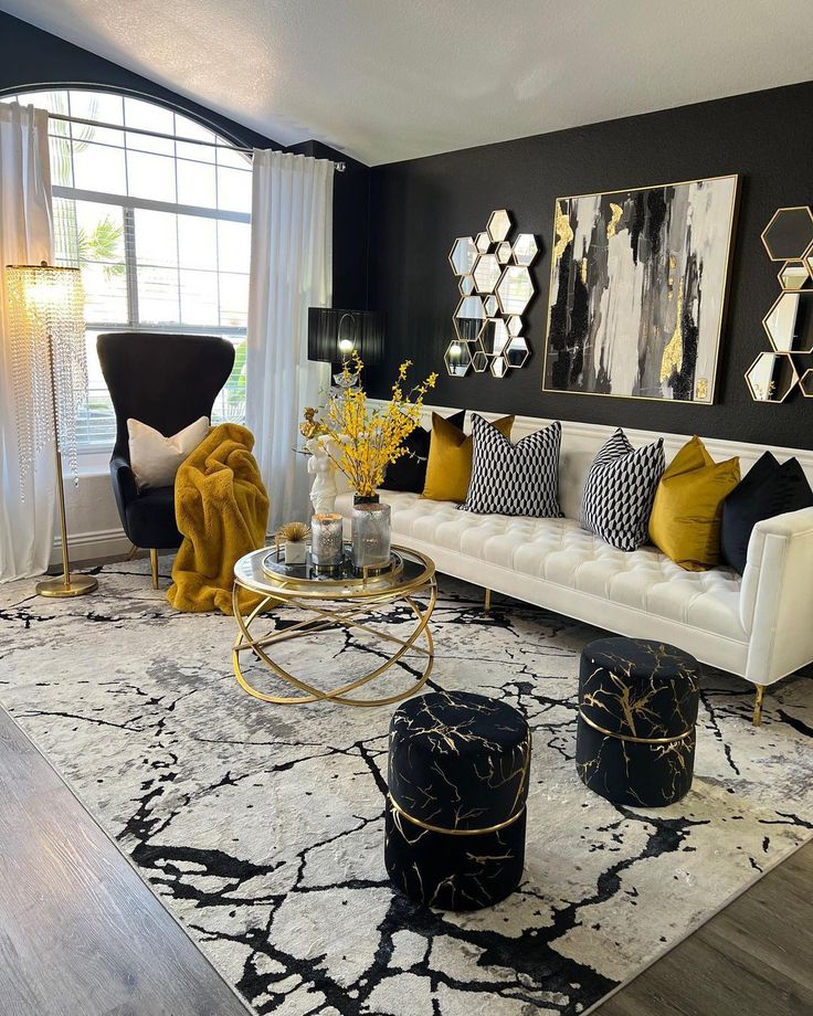 a living room with black and white furniture, gold accents and paintings on the wall