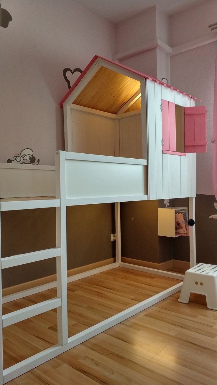 there is a bunk bed with a pink roof and ladders on the bottom floor