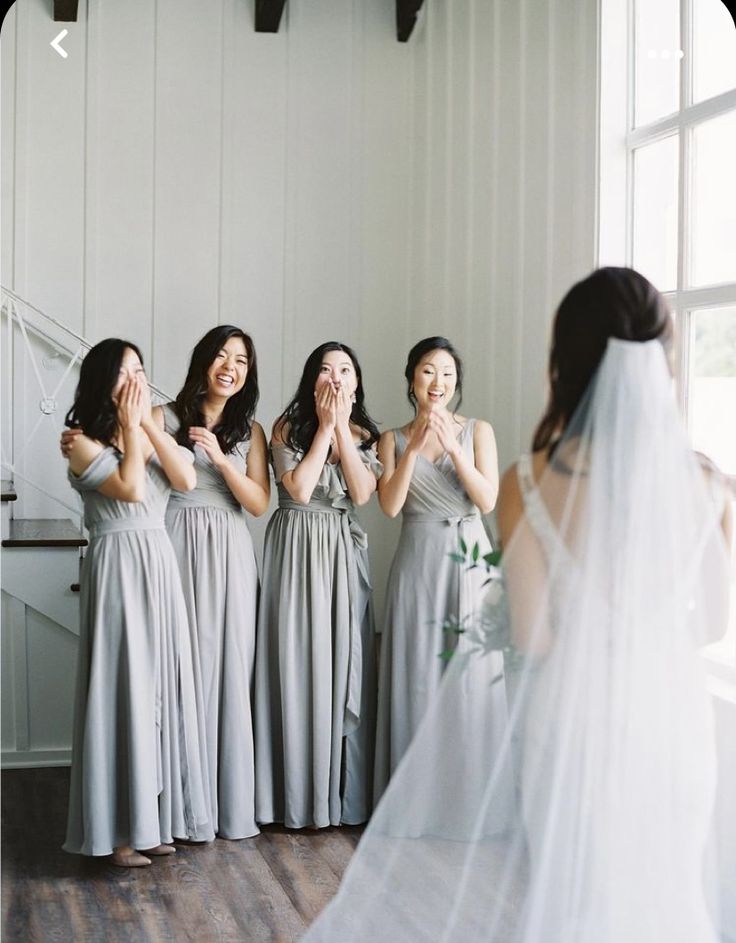 a group of women standing next to each other in front of a window with their hands together