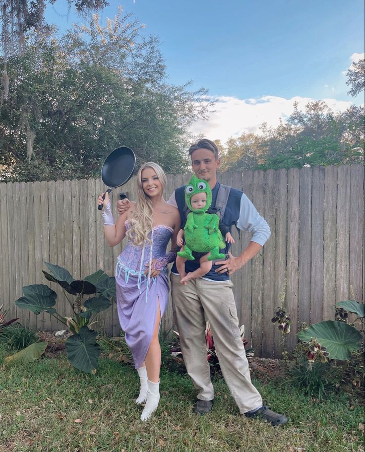 a man and woman dressed up as princess aurora and frog prince, standing in front of a fence