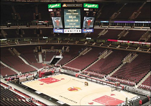 an empty basketball court with red seats and scoreboards on the sidelines in a stadium