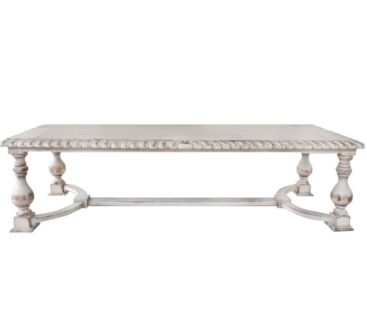 a white table with wooden legs and an ornate design on the top, against a white background