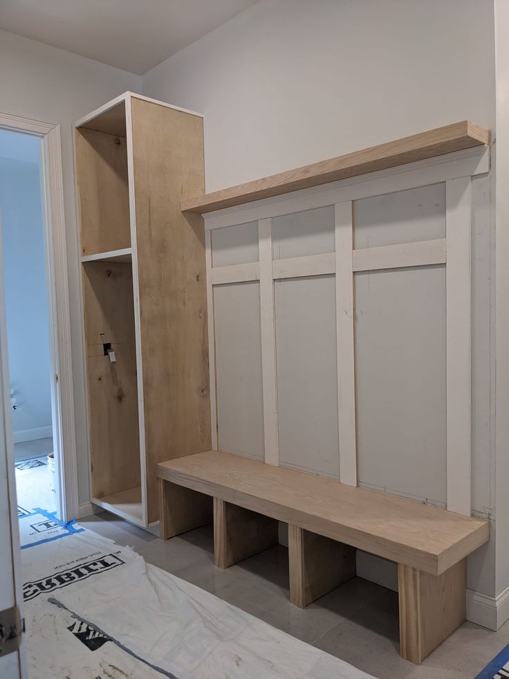 a wooden bench sitting in the middle of a room next to a bookcase and closet