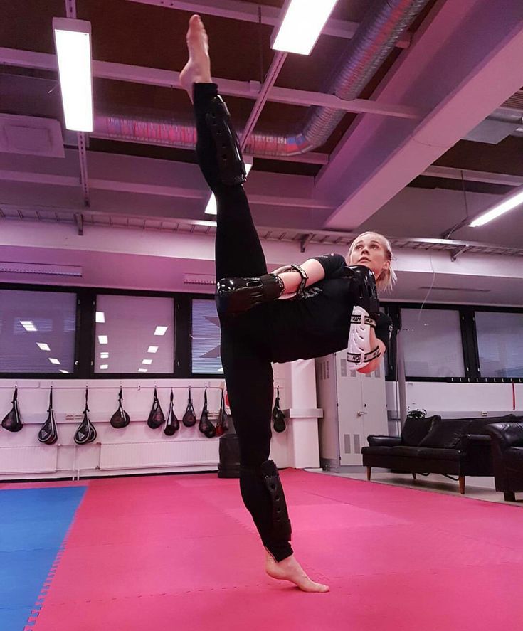 a woman doing a handstand on a pink mat in an indoor gym area